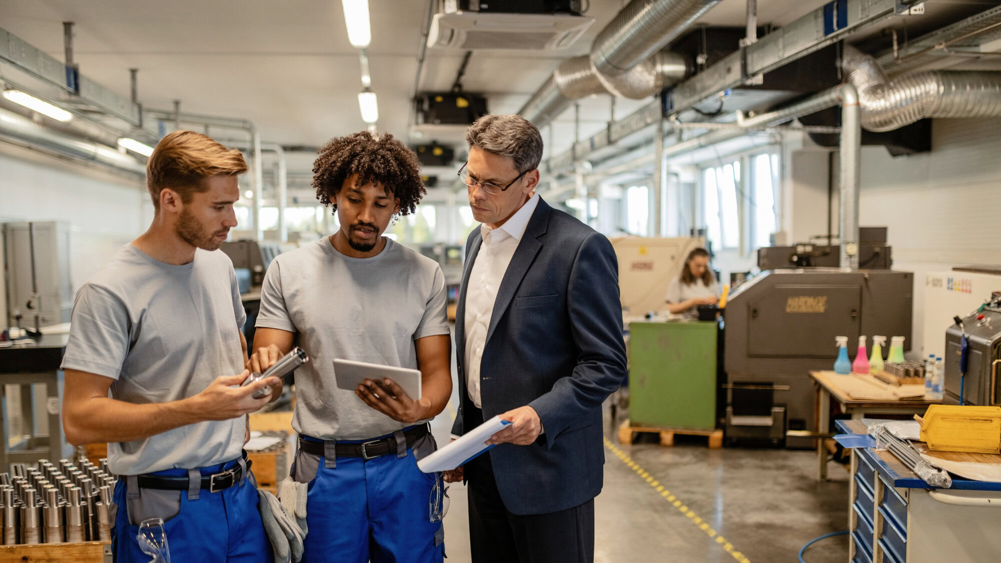 Der Weg zur papierlosen Fertigung. 4 mid adult manager two metal workers cooperating while analzying finished steel product using digital tablet industrial building scaled